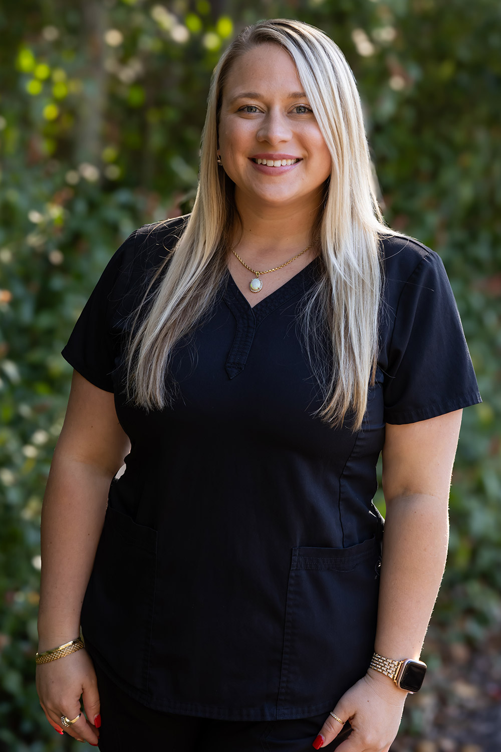 Brittney, Dental Assistant at DeLand Family Dental, smiling outdoors in black scrubs.