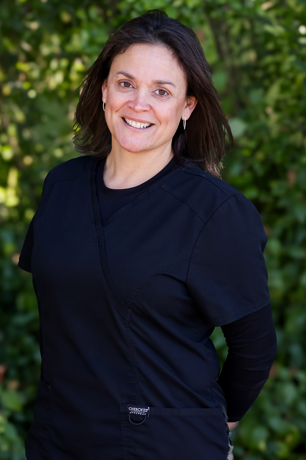 Julie, Administrative Assistant at DeLand Family Dental, smiling outdoors in black scrubs.