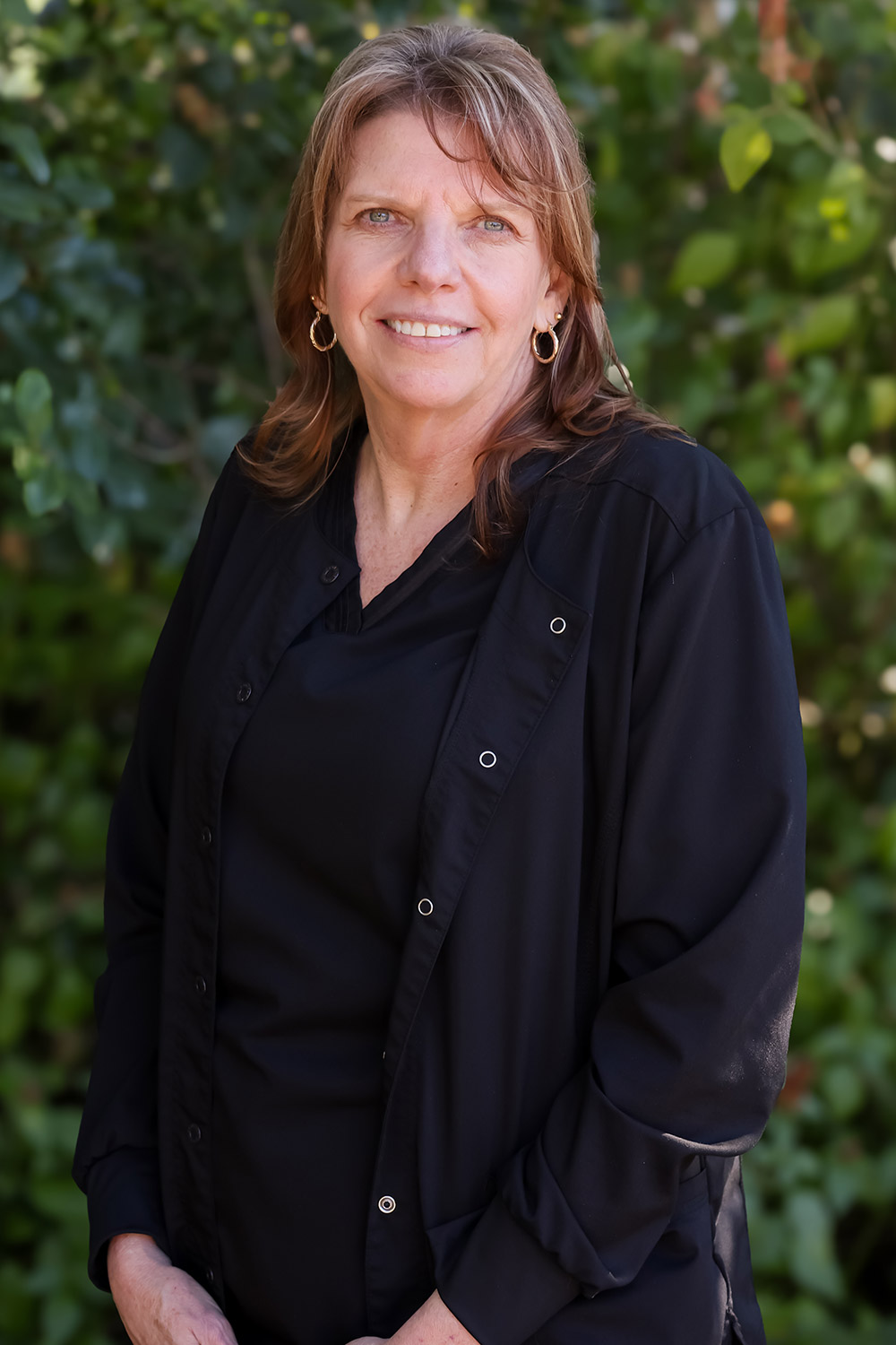 Stacey, Office Manager at DeLand Family Dental, smiling outdoors in black scrubs.